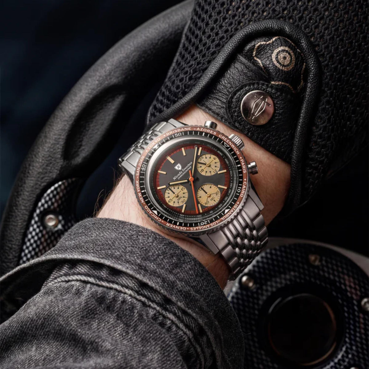 Nivada Grenchen Chronoking watch with a copper bezel worn on a wrist, positioned against a steering wheel and black leather driving glove
