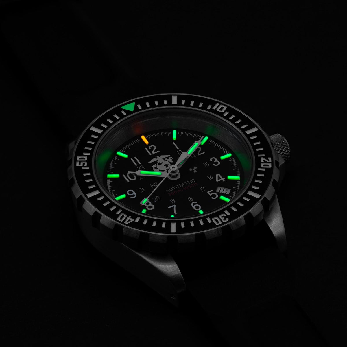 Marathon GSAR Official USMC WW194006SS-0230 automatic timepiece showing illuminated tritium gas tubes on black dial in low light
