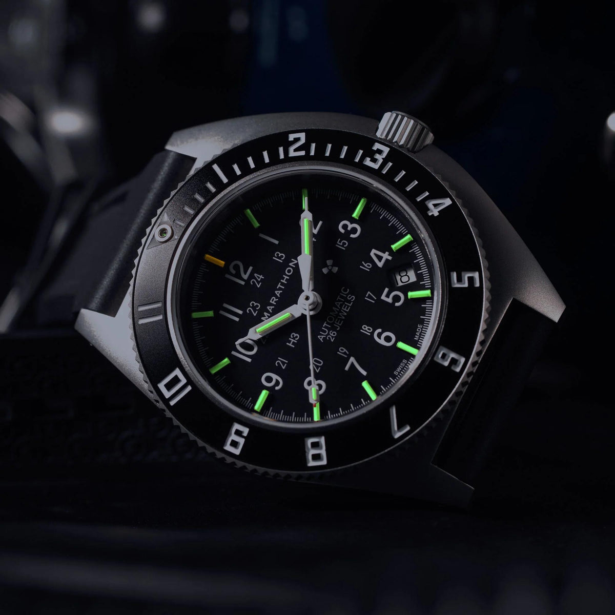 Marathon Navigator SSNAV-D WW194030SS-0130 automatic watch showing glowing tritium gas tubes on black dial in dark setting