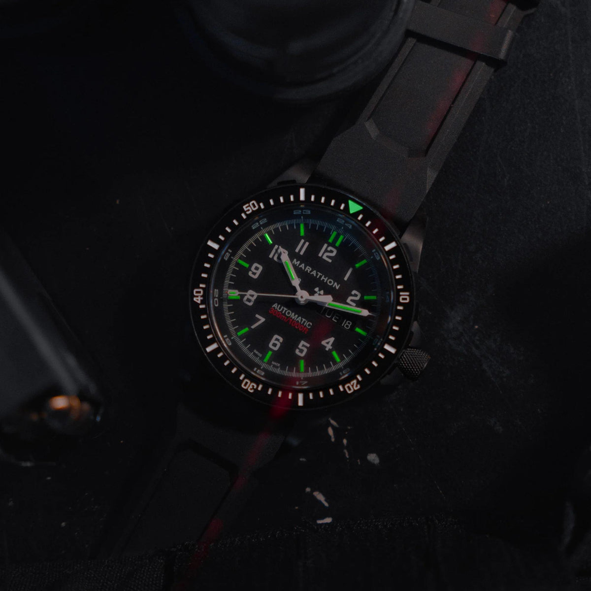 Marathon Jumbo Day/Date Anthracite WW194021BK-0130 automatic watch showing glowing tritium gas tubes on black dial in low light