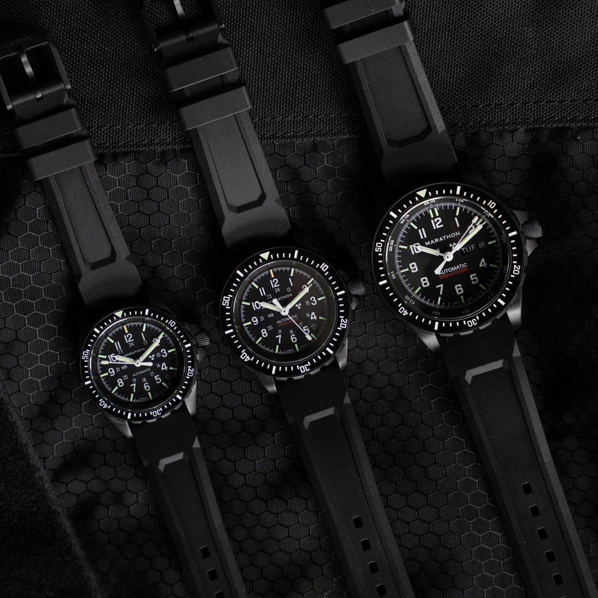 Marathon SAR Anthracite WW194026BK-0130 automatic watch shown alongside similar models on a textured background