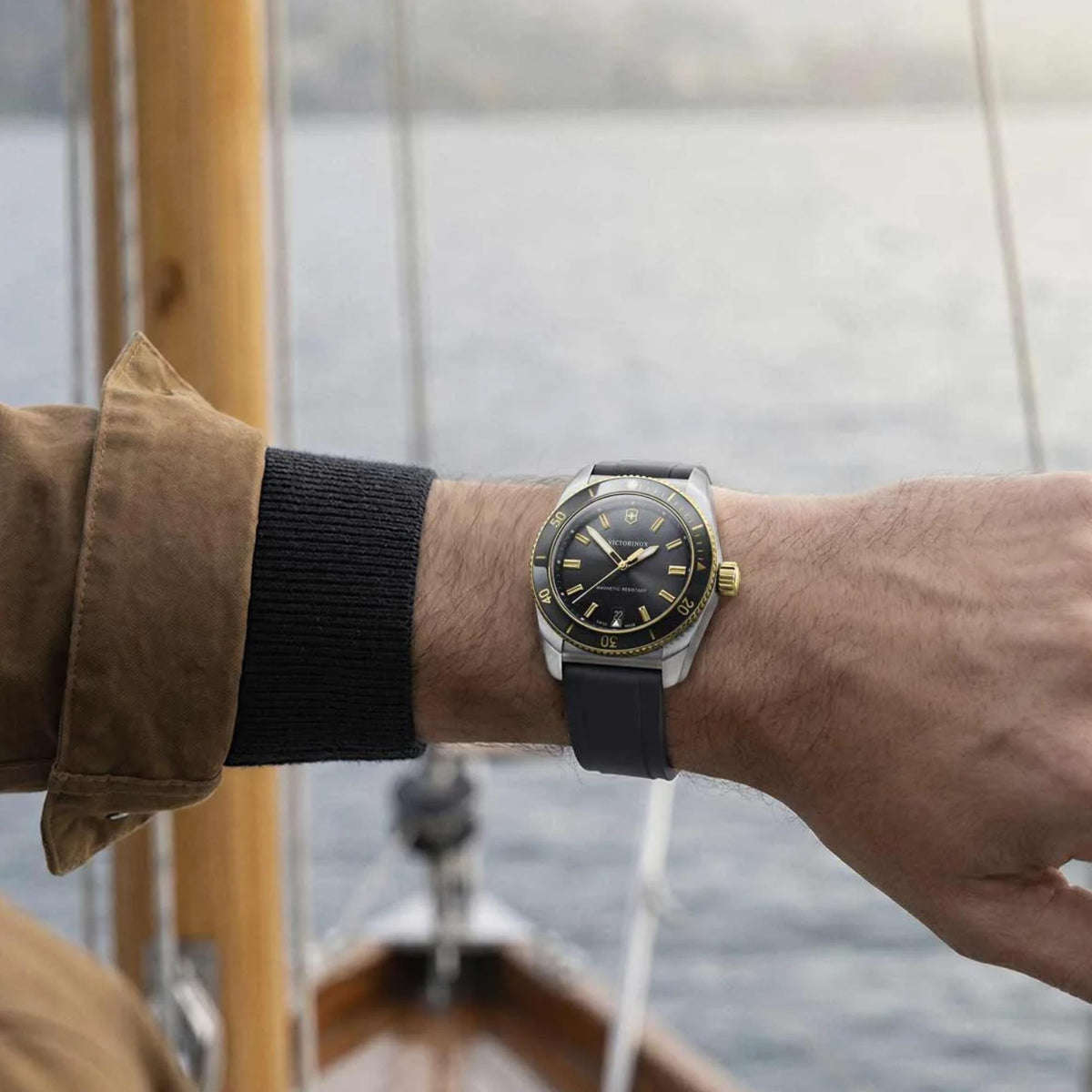 Victorinox Maverick 242099 mens watch on wrist lifestyle shot with black dial, gold trim, and black rubber strap outdoors