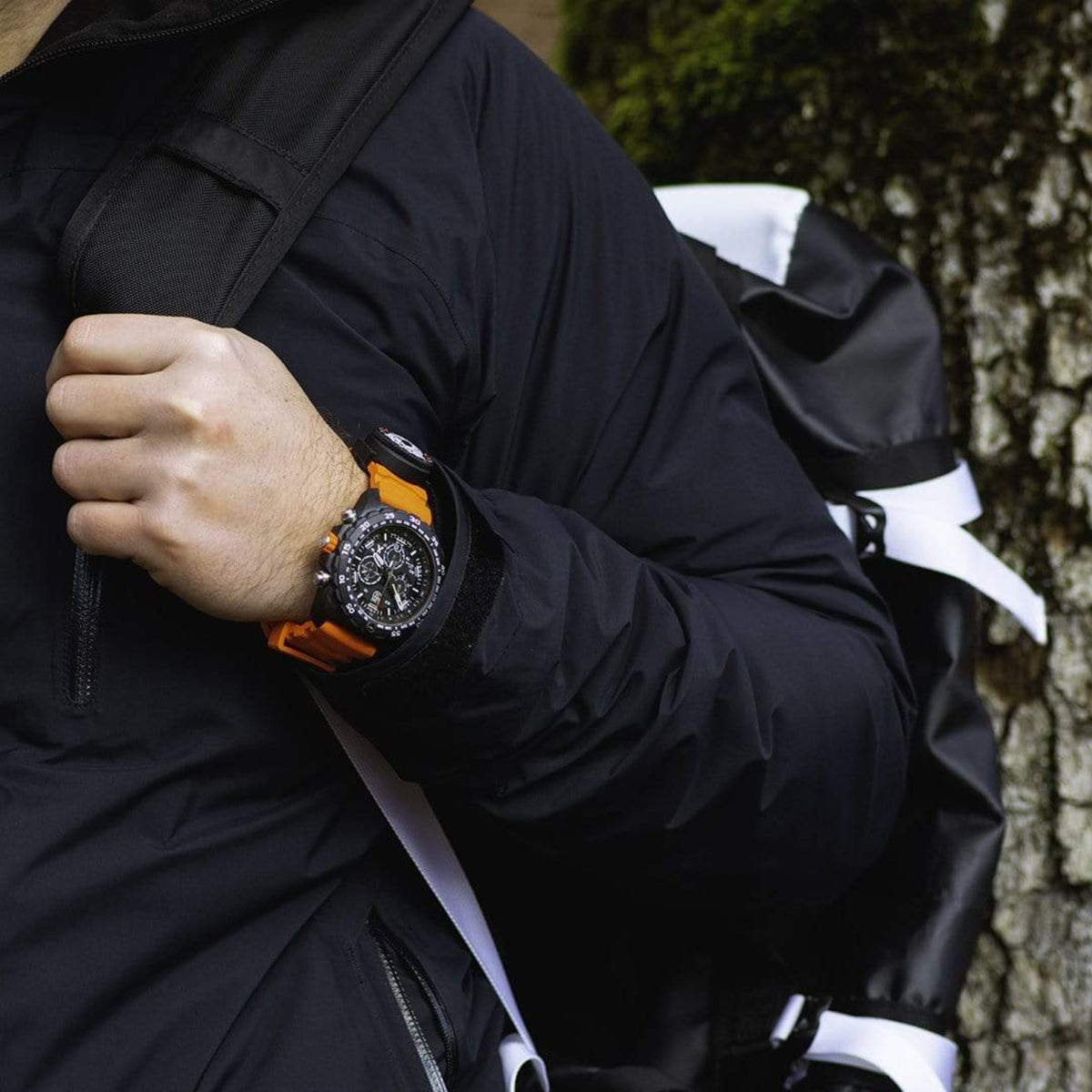 Hiker wearing a Luminox chronograph watch with bright orange rubber strap and backpack