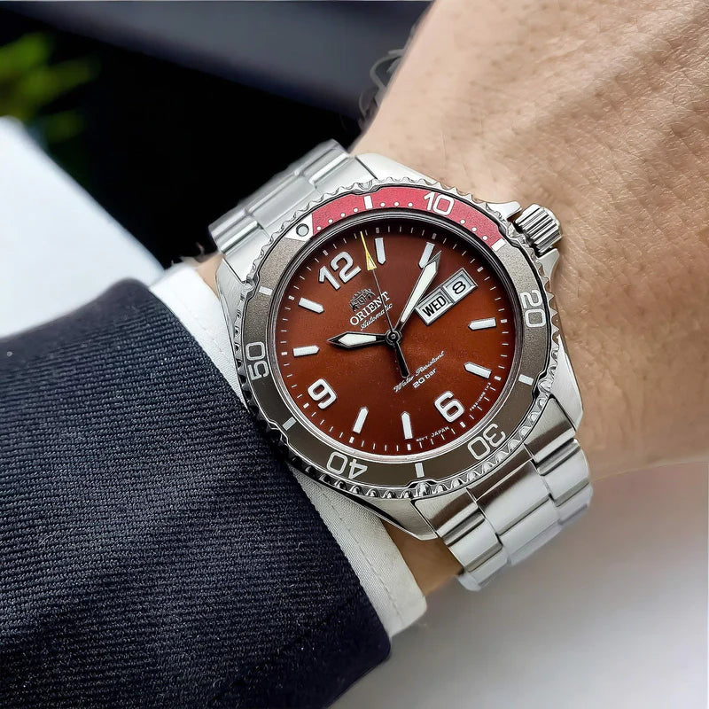 Men's stainless steel automatic watch on wrist, red bezel, brown dial, date window