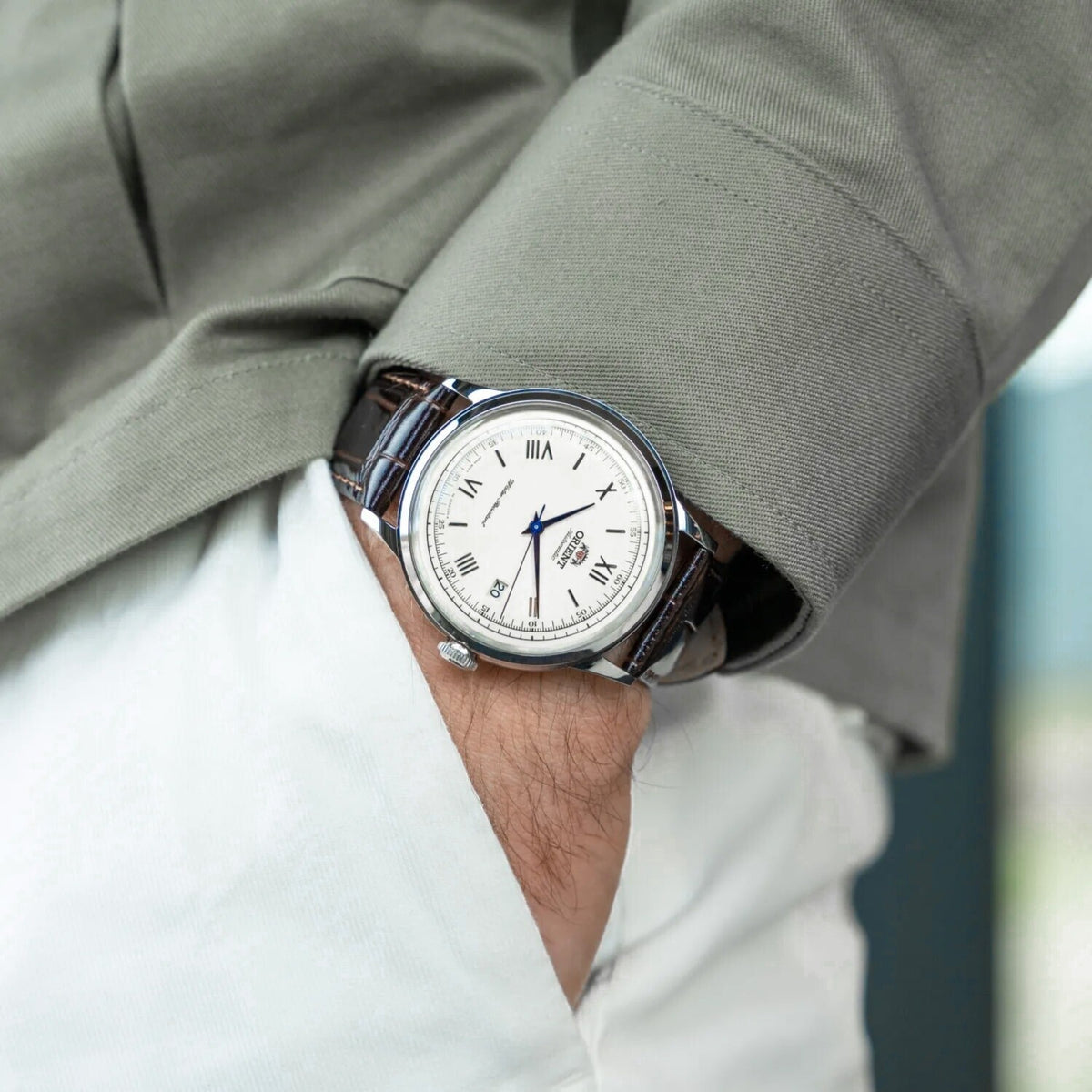 Orient Bambino TAC00009W0 automatic mens watch featuring a white dial worn on a wrist with a gray jacket sleeve