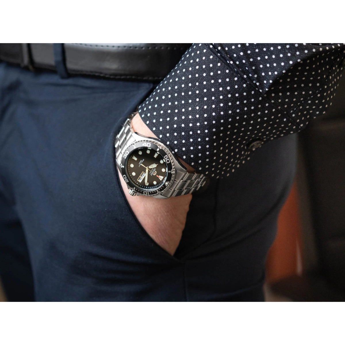 Men’s automatic dive watch on wrist with black dial, stainless bracelet, and crown