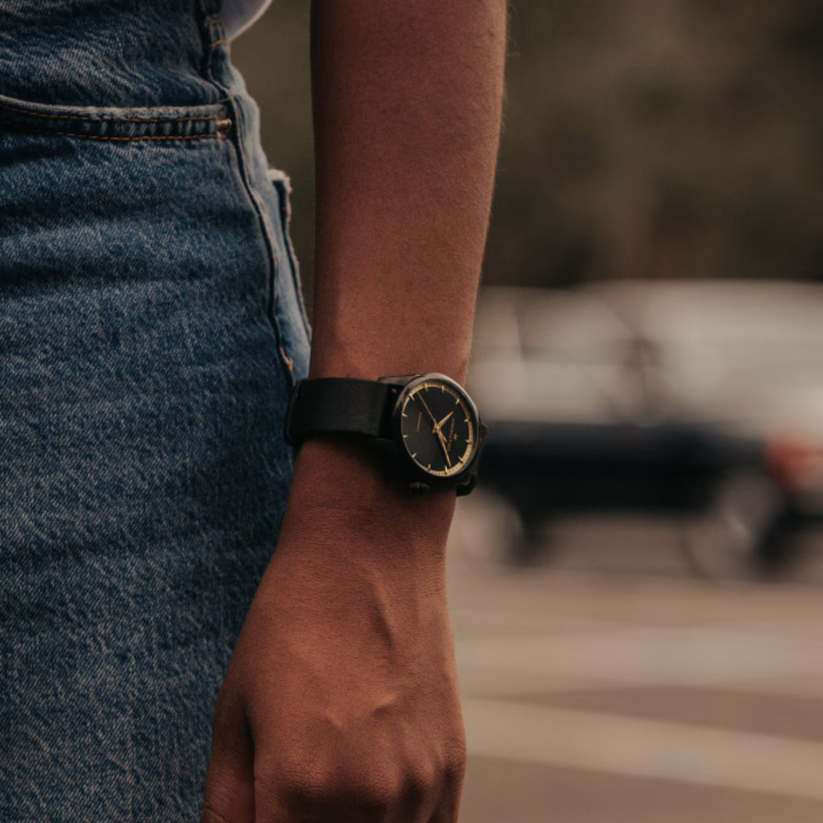 Automatic watch on wrist with black leather strap and black dial with gold hands
