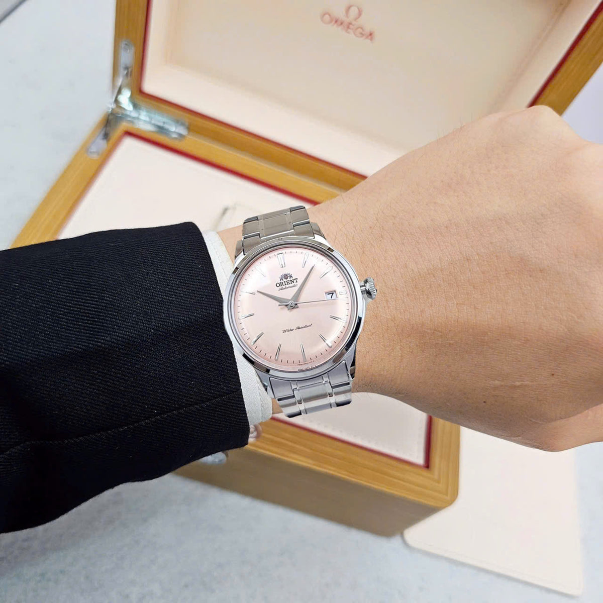 Orient Bambino RA-AC0M11Y30B 38mm self-winding timepiece with pink dial styled on a wrist in formal wear