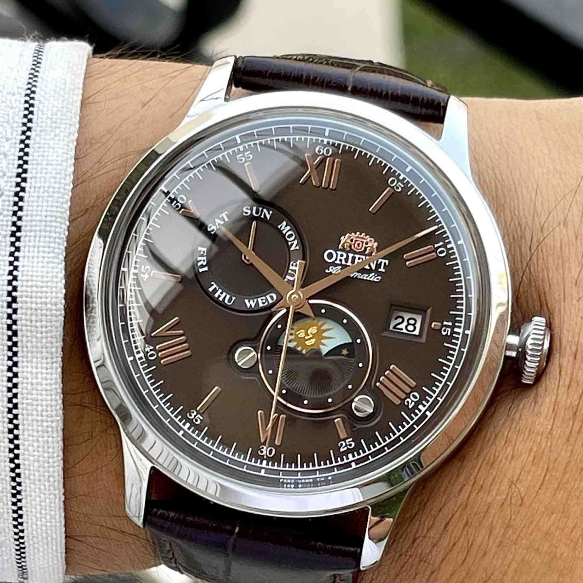 Orient Bambino Sun & Moon RA-AK0804Y30B automatic watch on wrist with brown sun-moon dial and dark brown leather strap