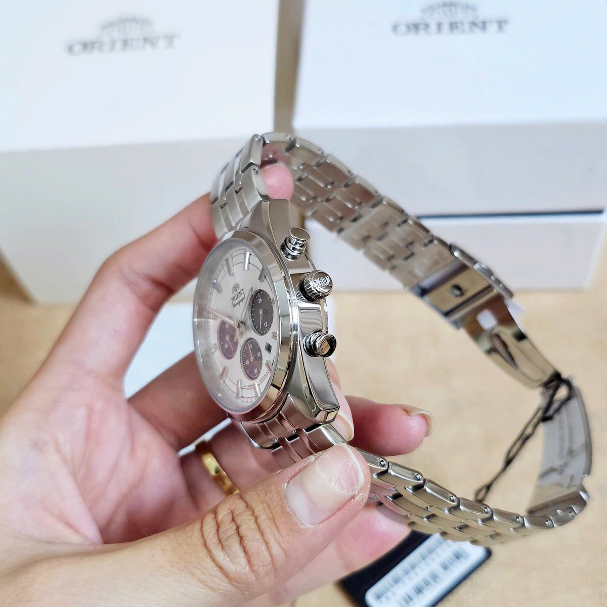 Men’s solar chronograph watch with steel bracelet and case back detail in hand