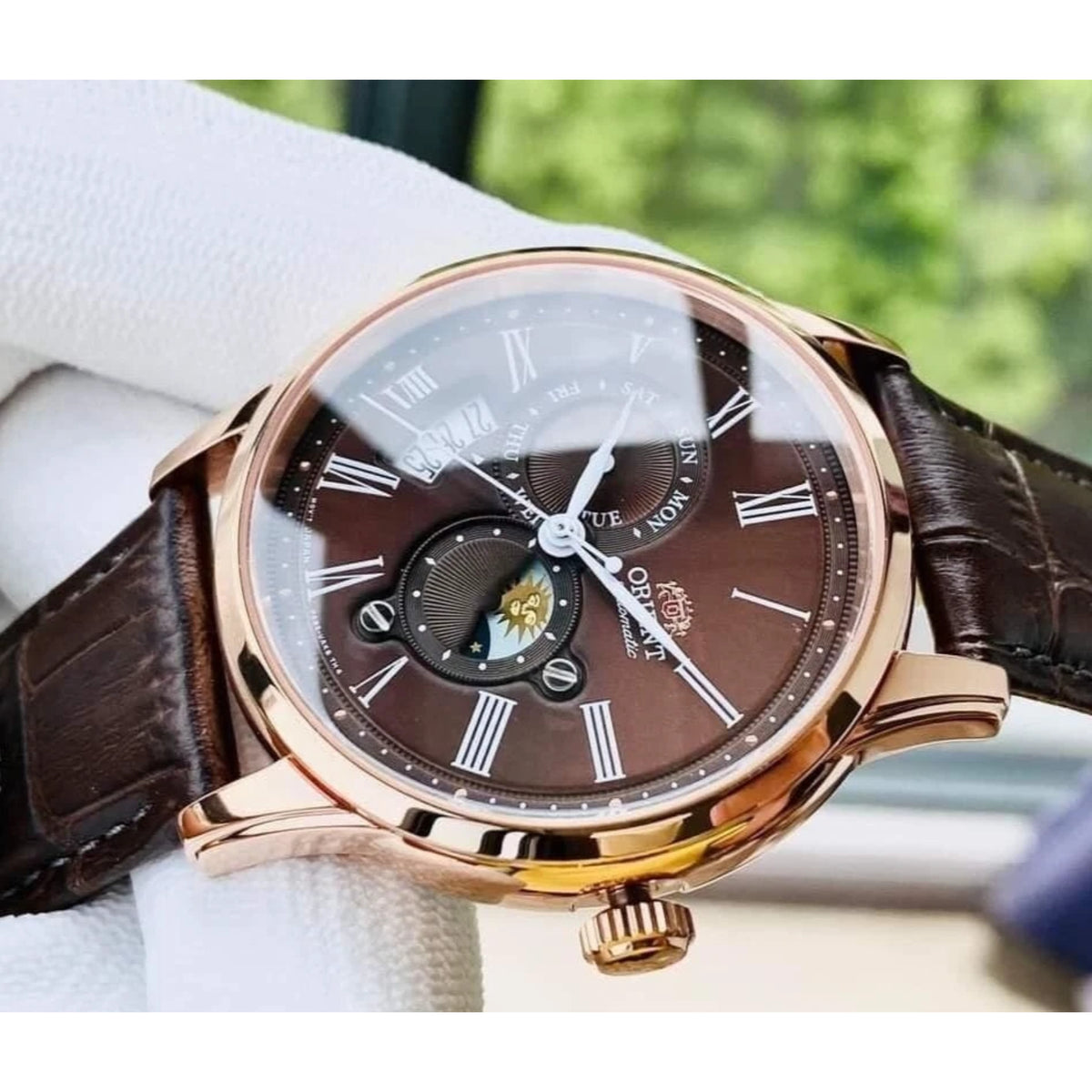 Orient Bambino RA-AK0009T30B automatic wristwatch close-up: brown leather strap, rose-gold case, dark dial with Roman markers
