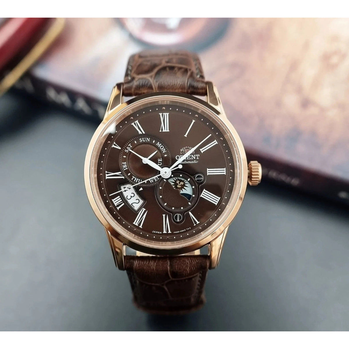 Orient Bambino automatic wristwatch RA-AK0009T30B with brown leather strap and dark dial featuring sun and moon subdials