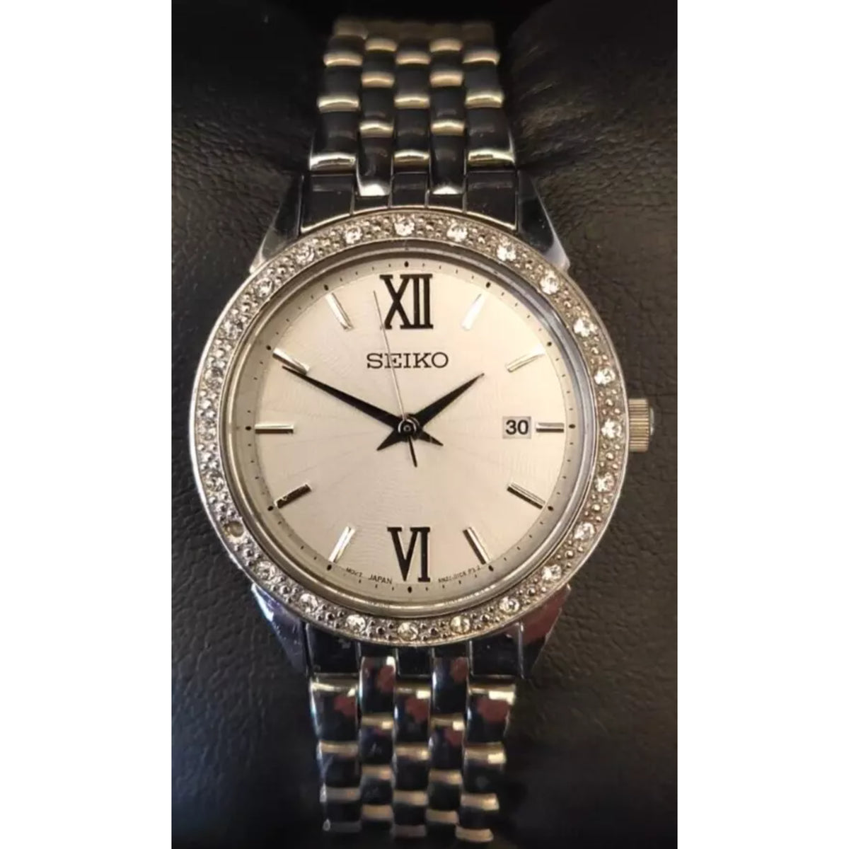 Front shot of the Seiko SUR695P1 ladies dress watch featuring a silver dial, Roman numerals at 12 and 6, a date window, and a sparkling crystal-set bezel.