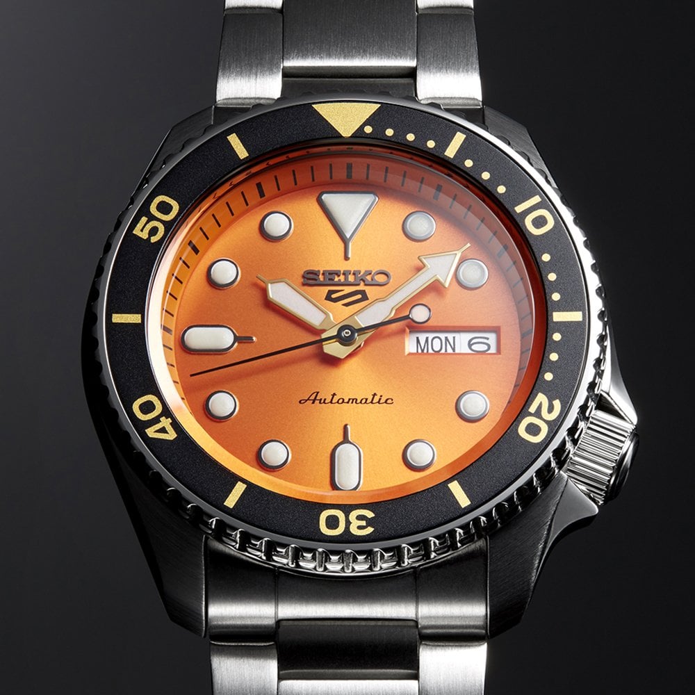 Men's Seiko stainless watch with orange dial, black bezel, right-side crown, bracelet links