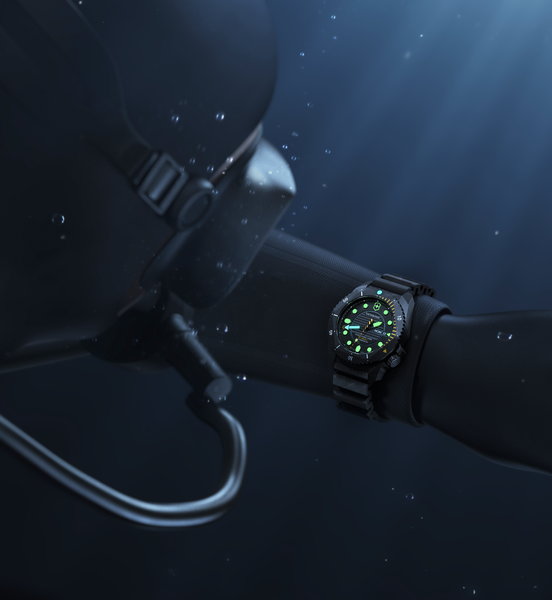 Scuba diver wearing Victorinox Dive Pro Automatic watch with glowing green luminescent dial underwater