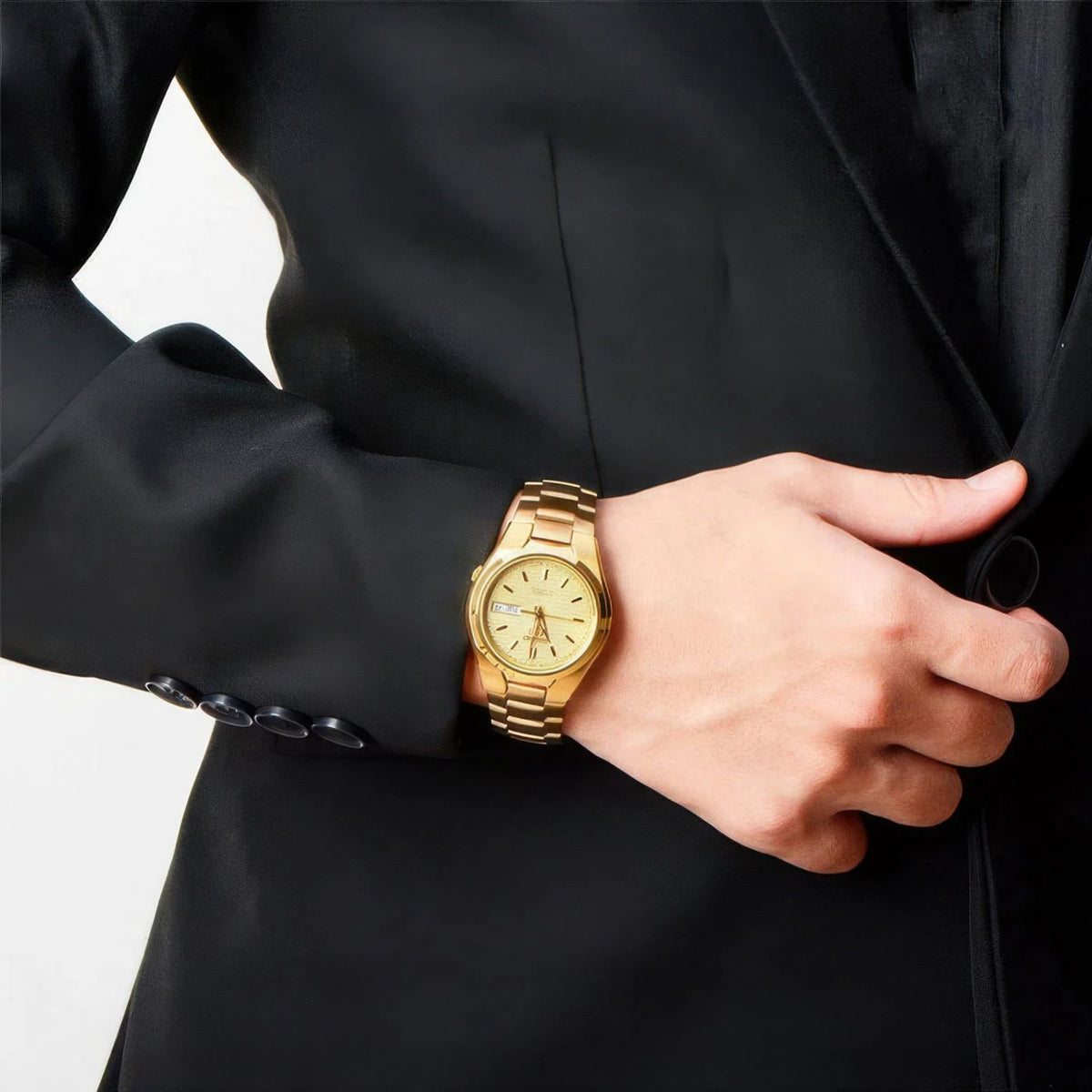Gold-tone wristwatch on a man's wrist with gold link bracelet and textured dial
