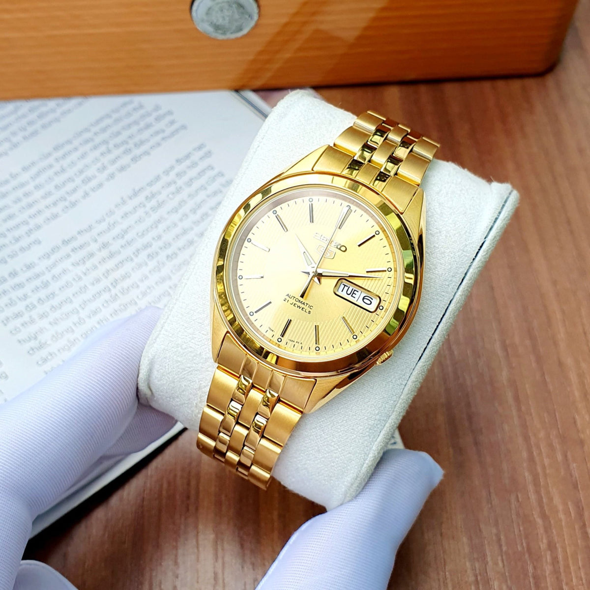 Gold-tone Seiko 5 automatic watch with white dial and stainless steel bracelet strap.