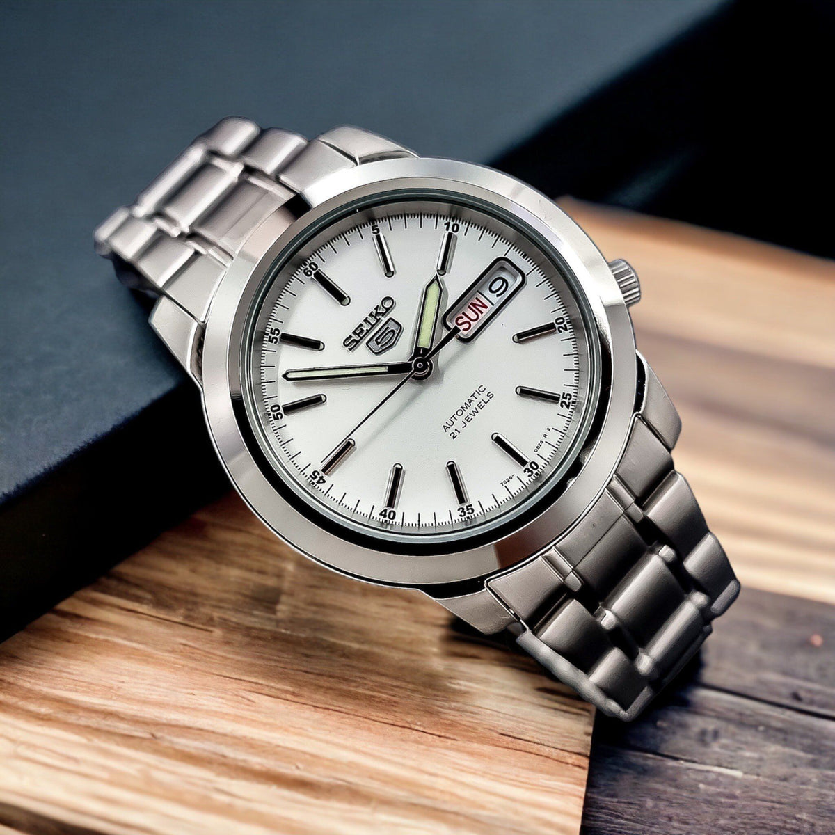 Seiko 5 Automatic SNKE49K1 angled perspective resting on wood background featuring white dial and steel casing