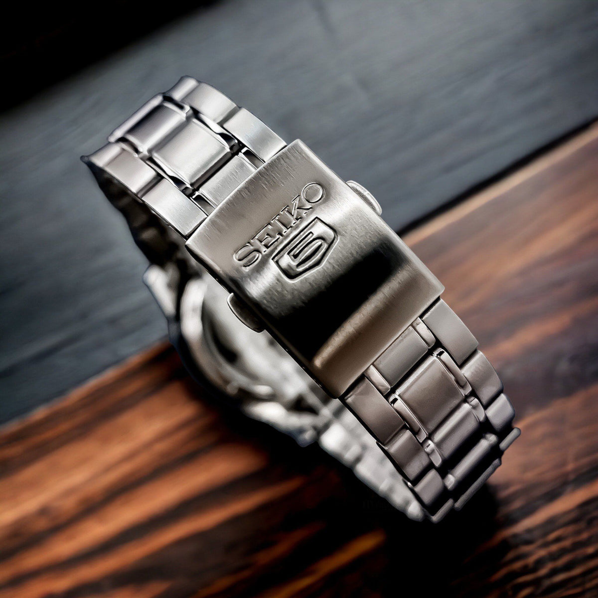 Seiko 5 Automatic SNKE49K1 close-up view of engraved brand logo on stainless steel bracelet clasp