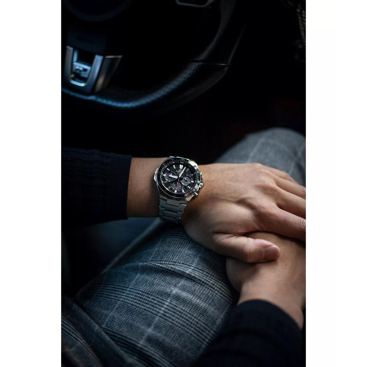 Men’s stainless steel solar chronograph watch on wrist, black dial with blue bezel and bracelet