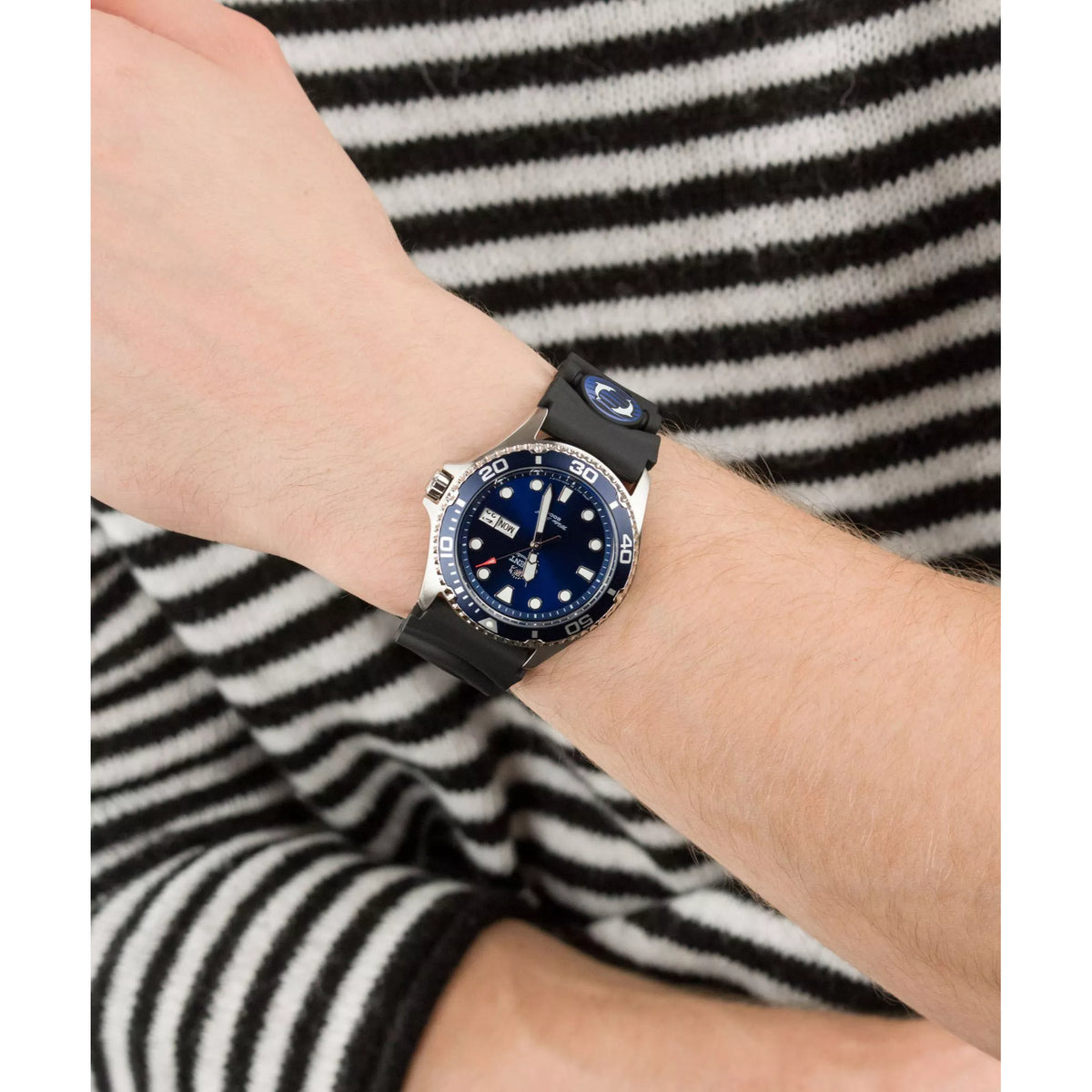 Close-up of automatic dive watch on wrist, blue dial and date window, black strap