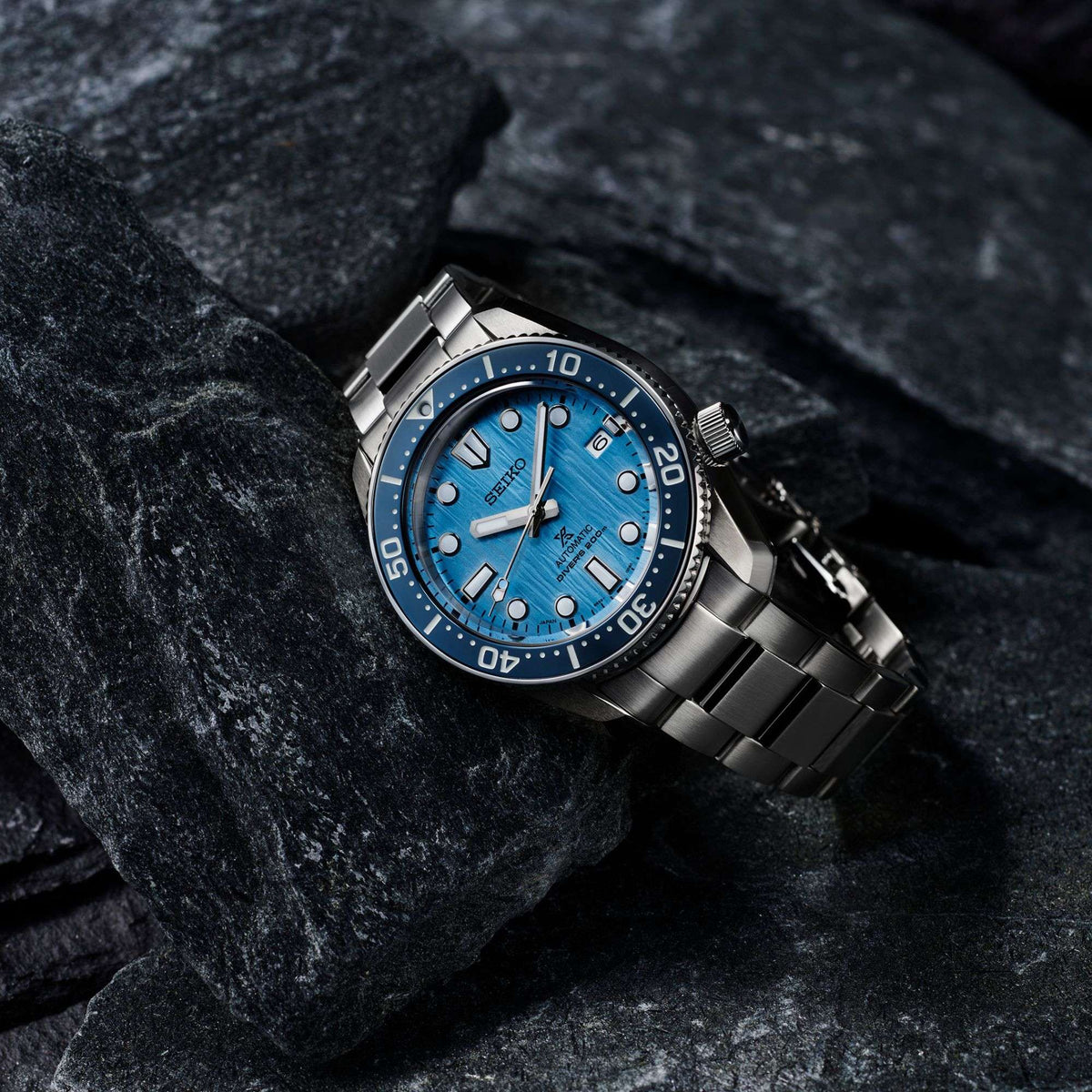 Men's diver watch close-up with textured blue dial and stainless steel bracelet