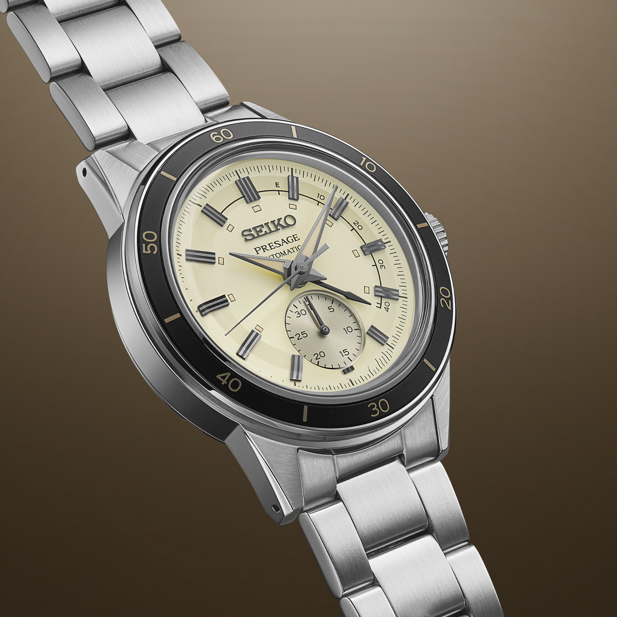 Men's stainless steel automatic watch with ivory dial, black bezel, and metal bracelet links