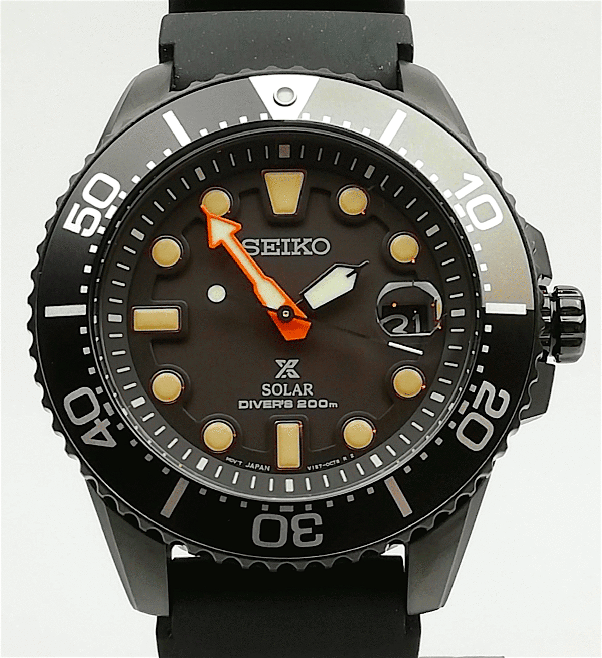 Black dial solar diver's watch with orange hands, date window, and rubber strap.