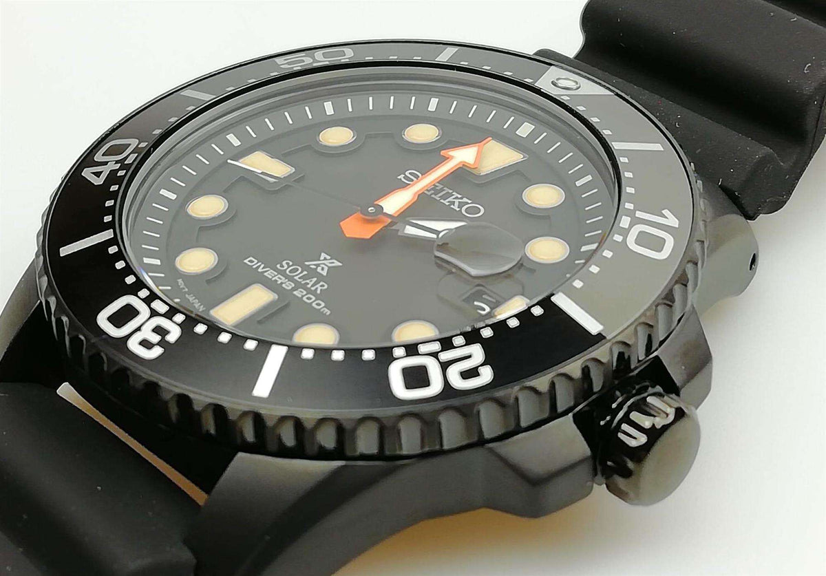 Gray and black dial solar diver's watch with orange-accent hands and rubber strap.