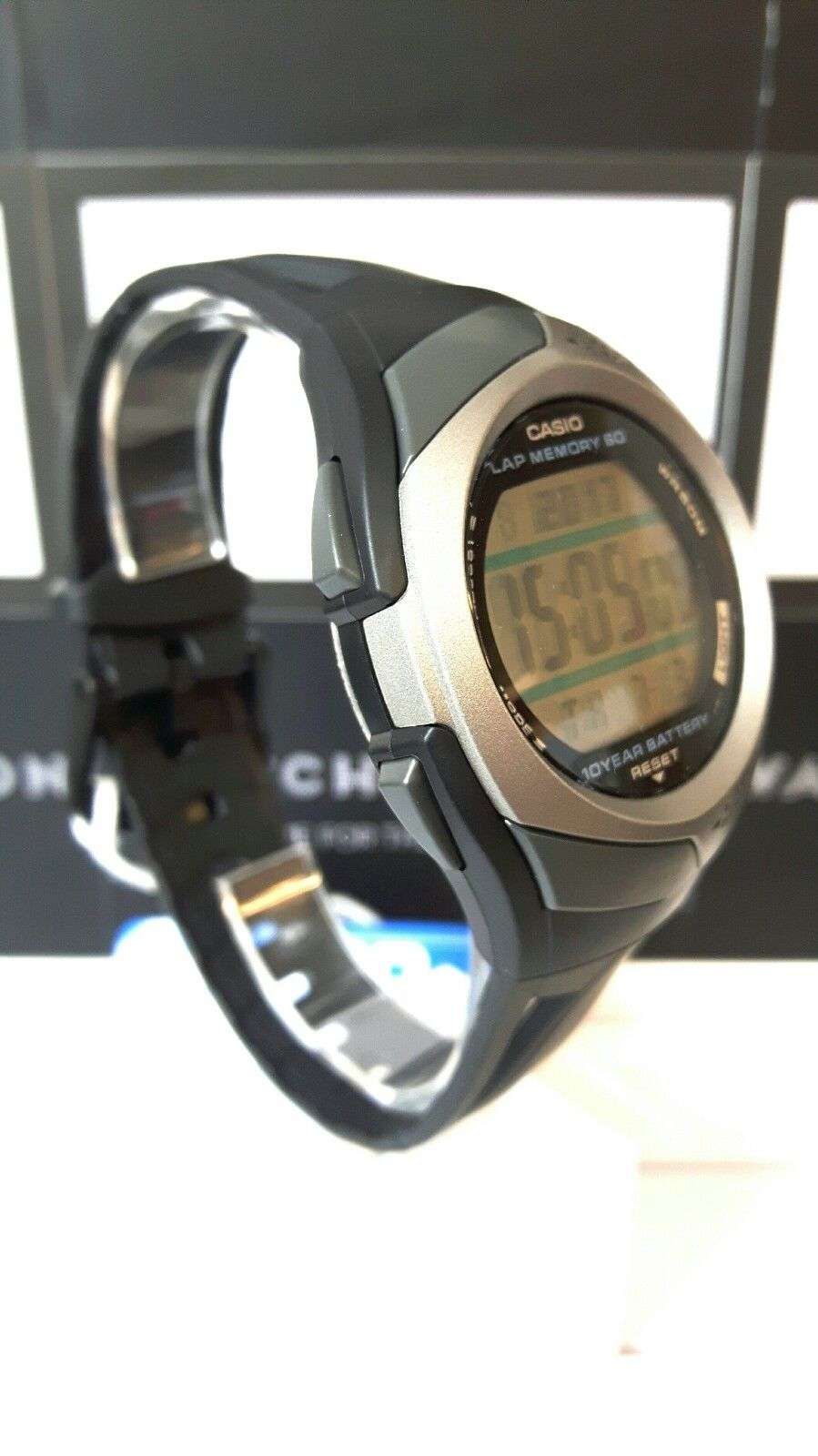 Men's digital sports watch with black resin strap, angled side view of round LCD