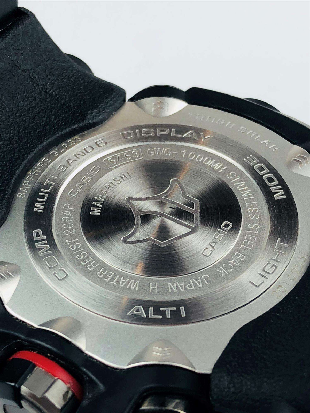 Metal watch caseback with embossed star logo and multi-band G-Shock text