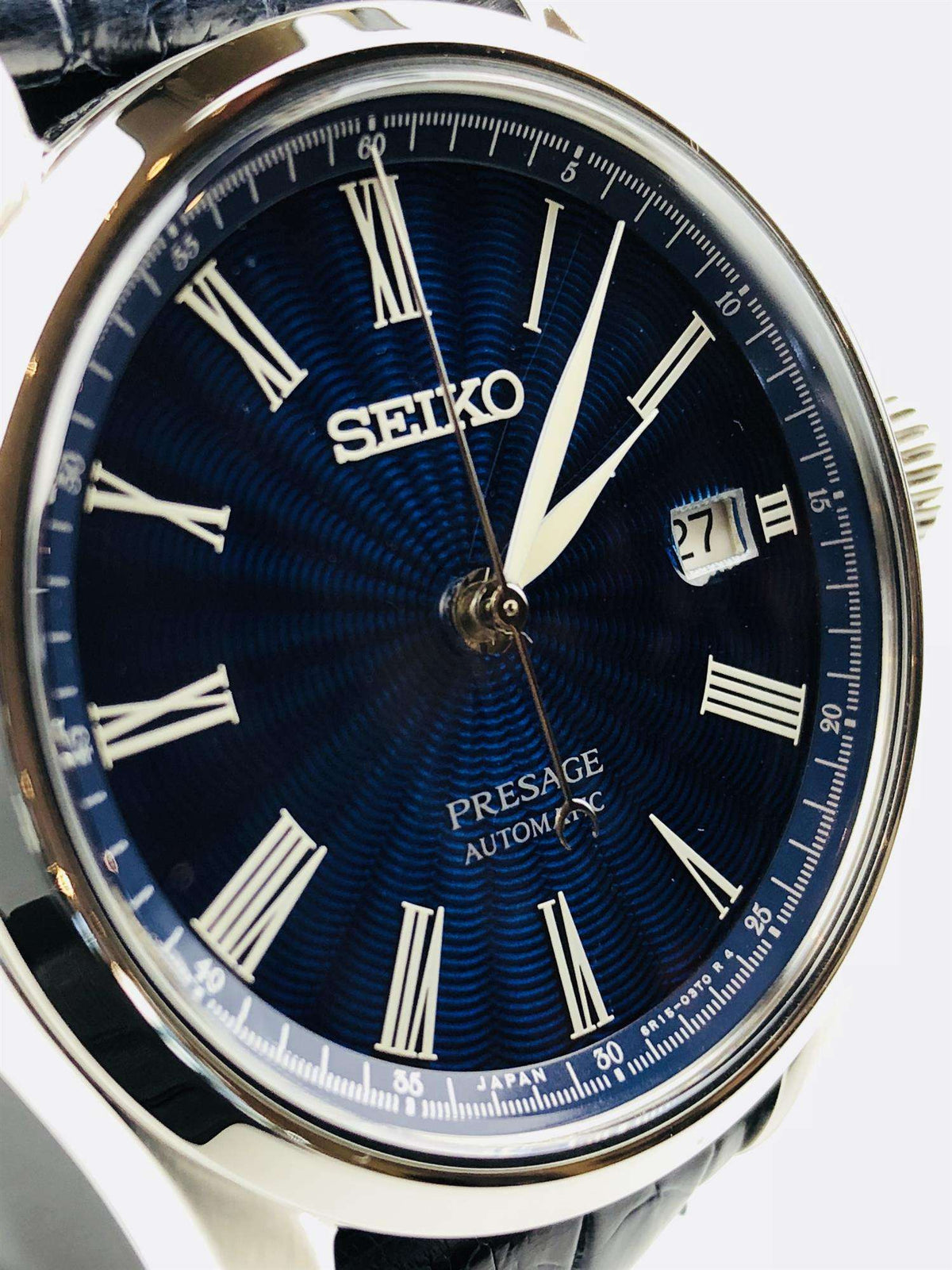 Men's automatic wristwatch with blue sunburst dial, Roman numerals, and date window at 27