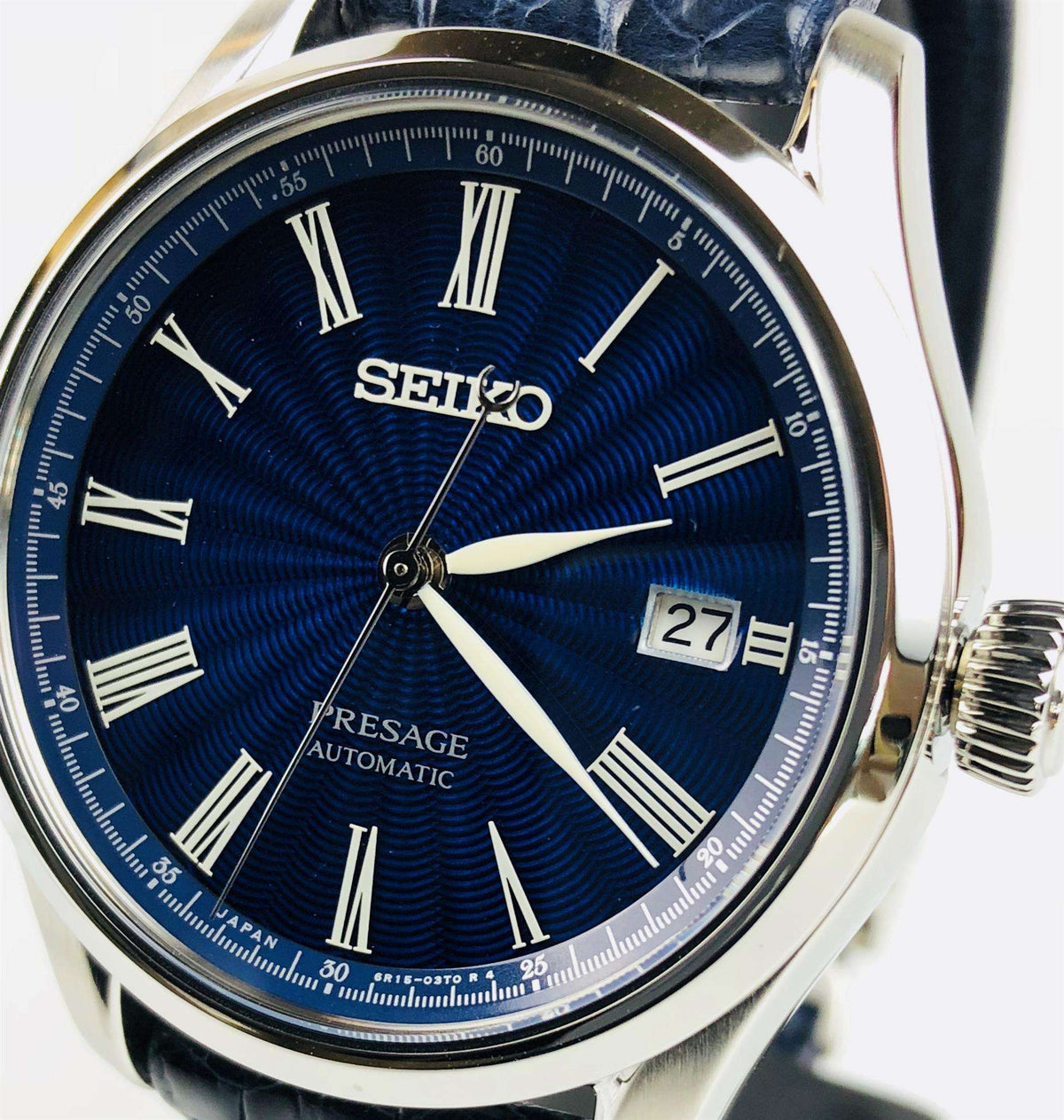 Men's automatic wristwatch, blue dial with Roman numerals, date window showing 27