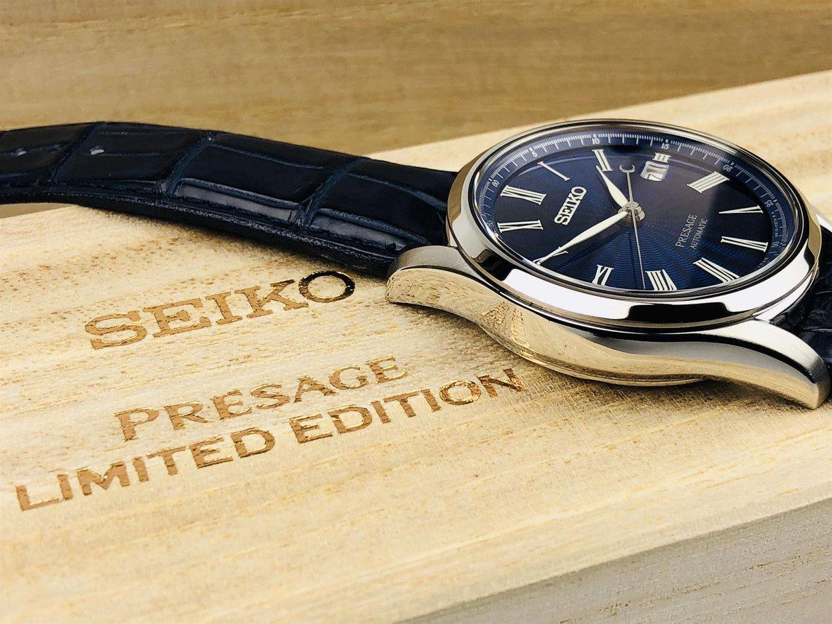 Men's automatic wristwatch with blue dial, Roman numerals, silver case, and black leather strap