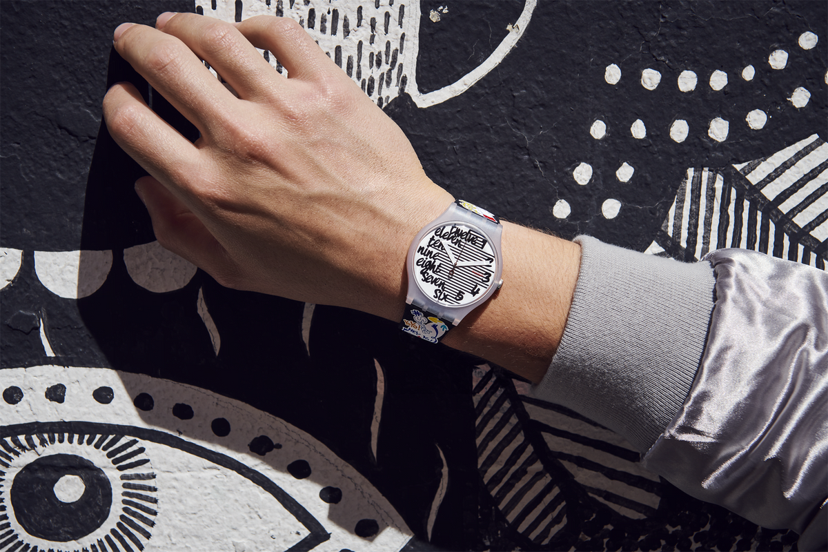 Round watch on wrist with white dial and black silicone band, silver-tone plastic case