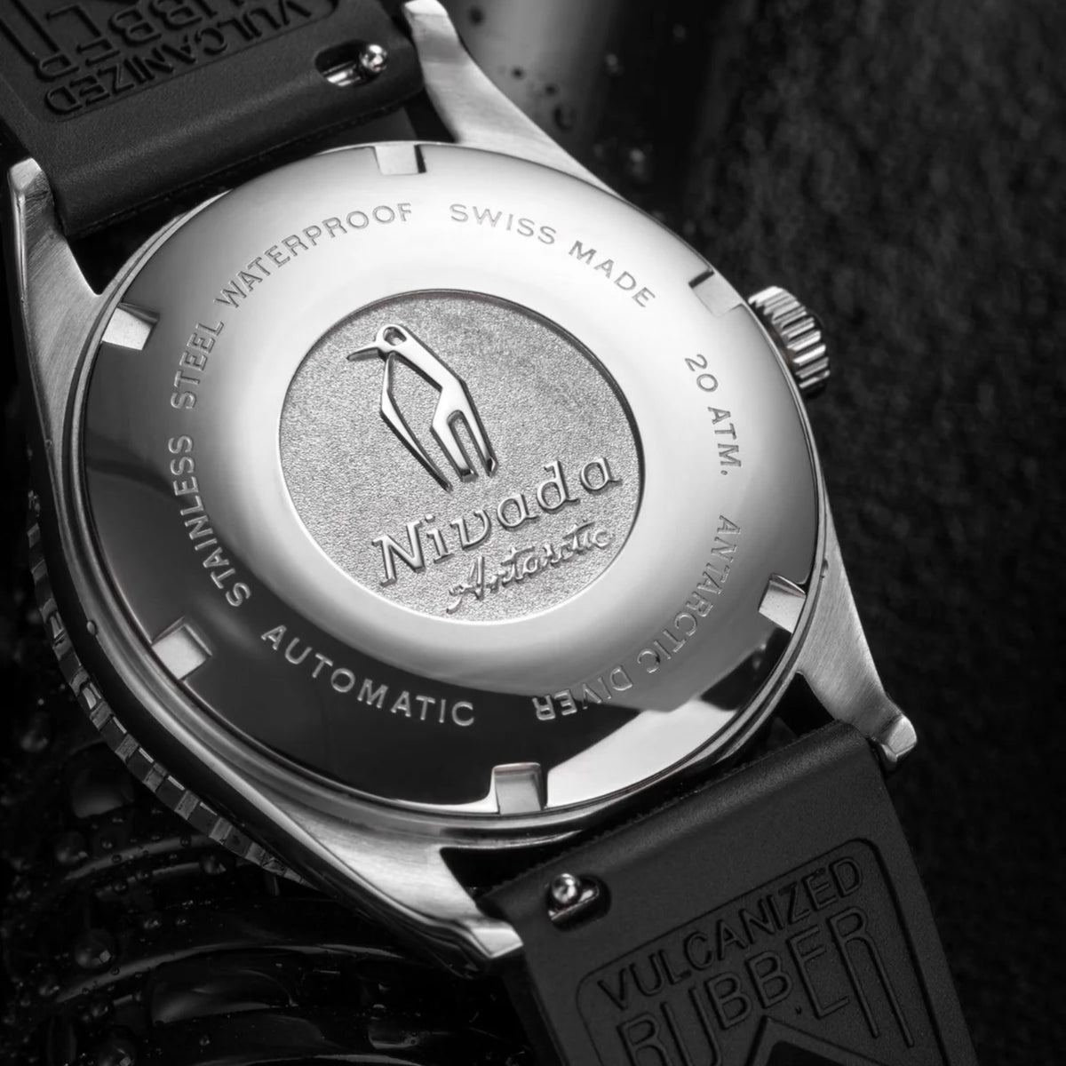 Brushed metal caseback with stamped diver icons and Vulcanized Rubber label on watch