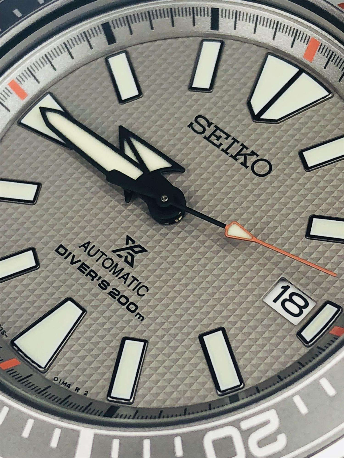 Close-up dial detail with sword hands, Seiko logo, and date window at 18