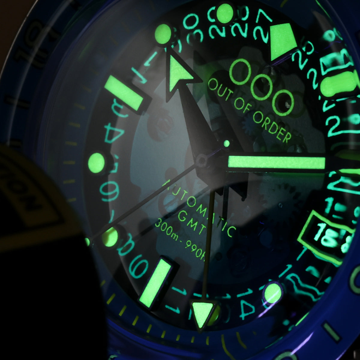 Men's automatic GMT watch dial closeup, luminous green markers on dark blue face