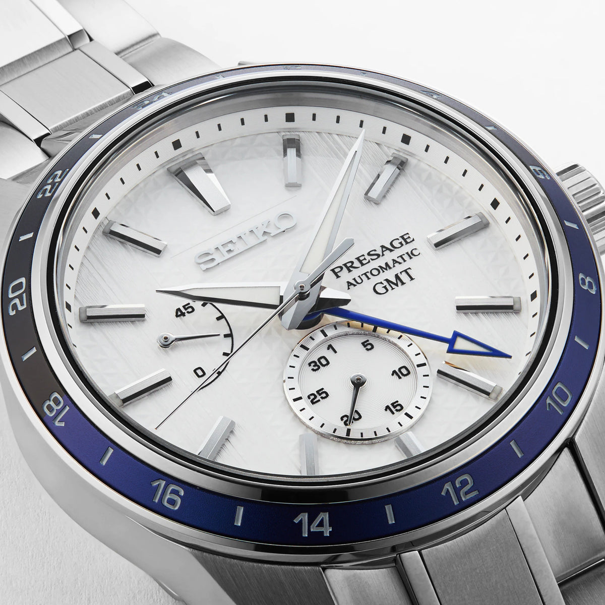 Seiko stainless steel GMT wristwatch with white dial, blue bezel, and silver hour markers