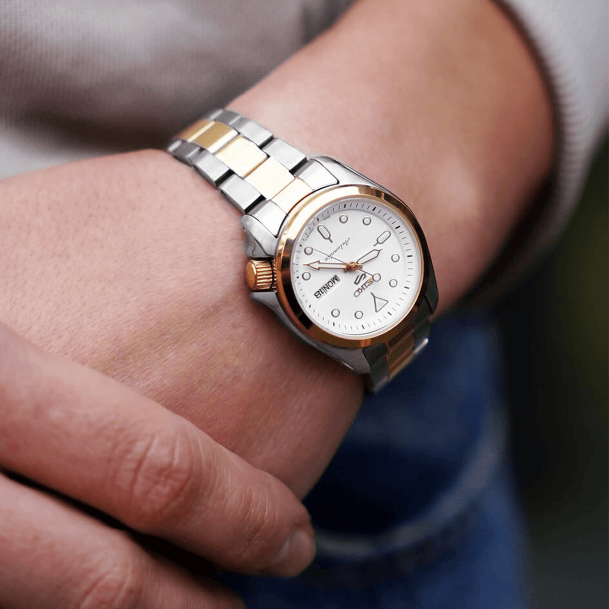 Two-tone stainless steel ladies automatic watch with white dial on wrist, gold indices