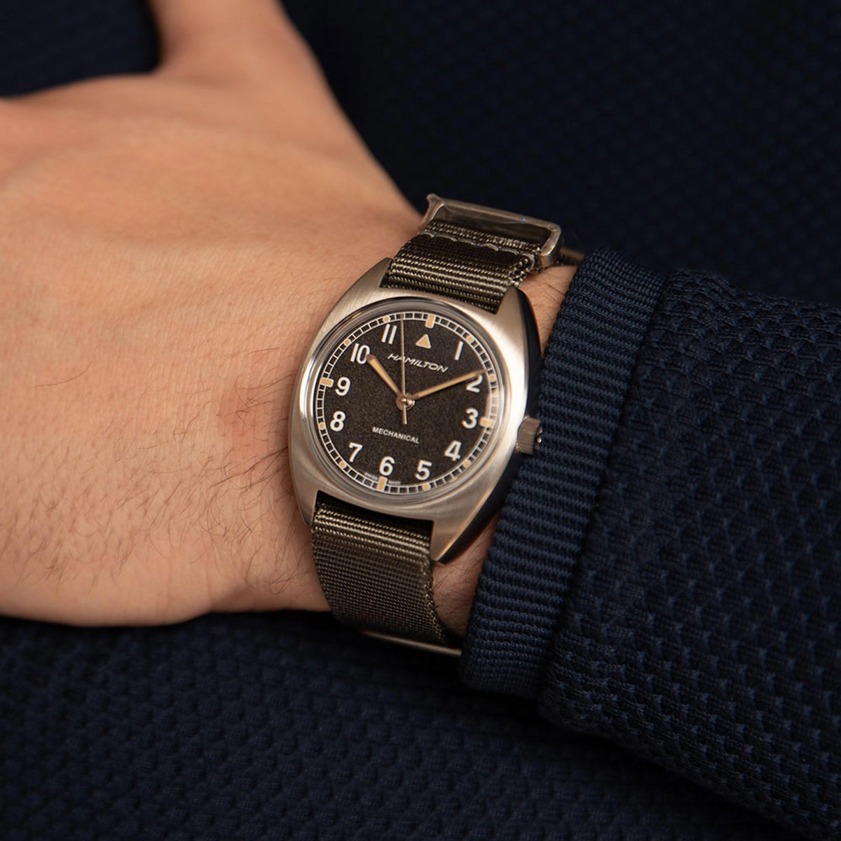 Hamilton pilot mechanical watch on wrist with black dial and dark green NATO strap