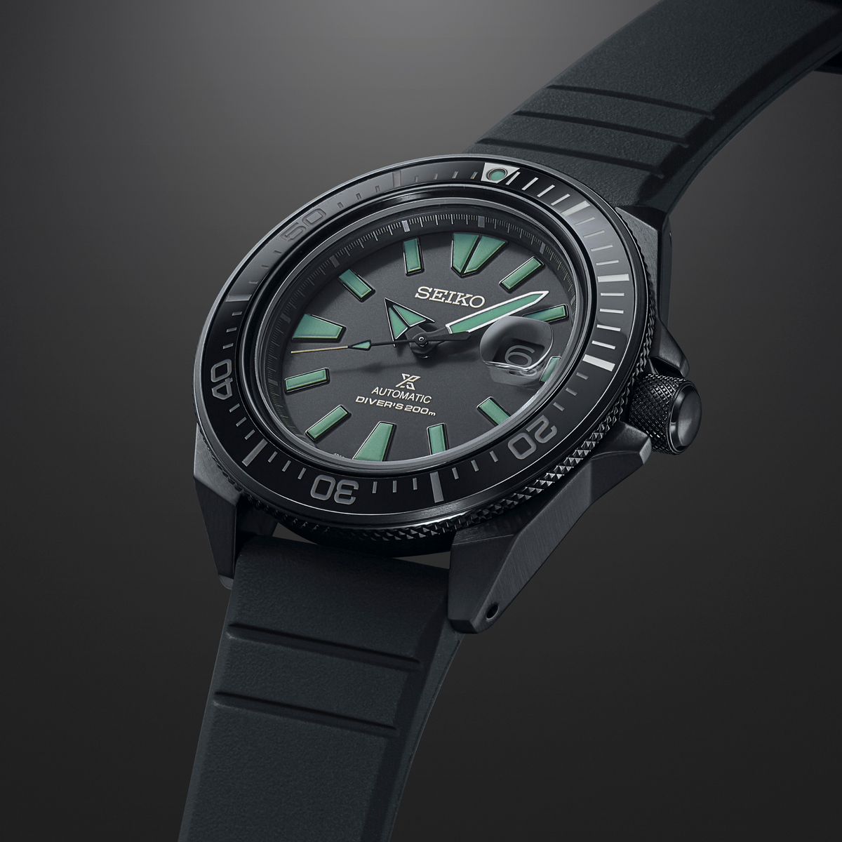 Angled black Seiko dive watch with green dial markers, black strap and rotating bezel