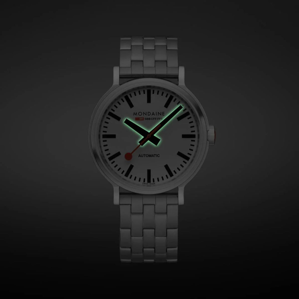 Dark-tone view of stainless steel automatic watch showing green lumed dial markers