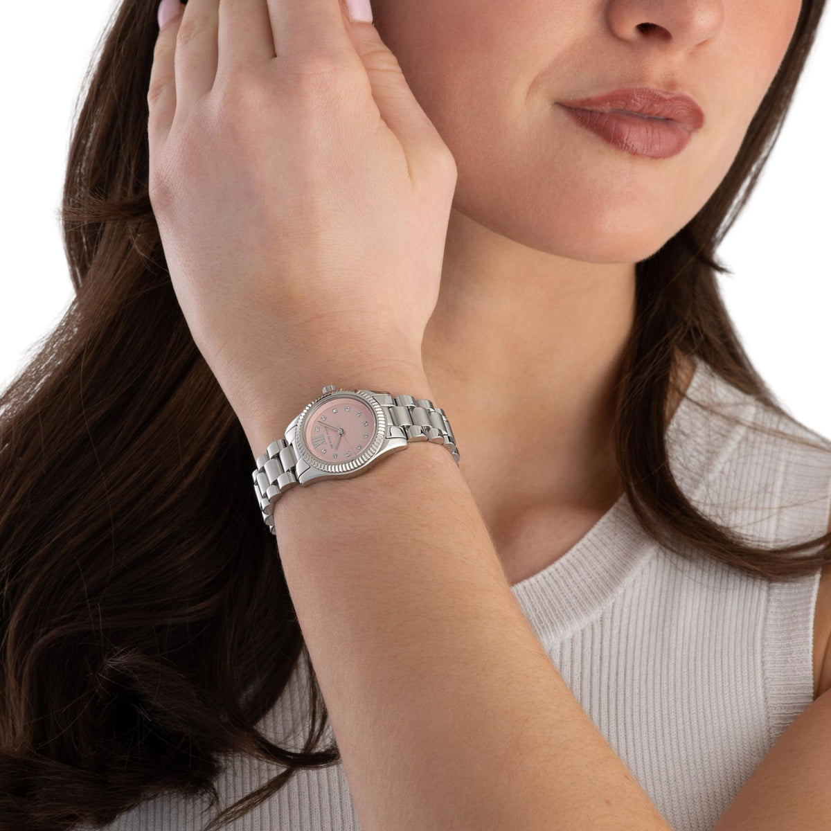 Women’s steel wristwatch on wrist with pink dial and Roman numeral markers