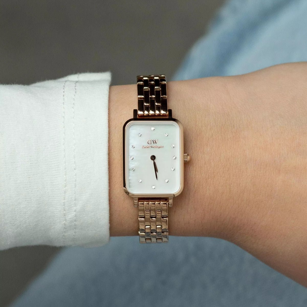 Ladies rose-gold quartz watch on wrist, square white mother-of-pearl dial and metal bracelet