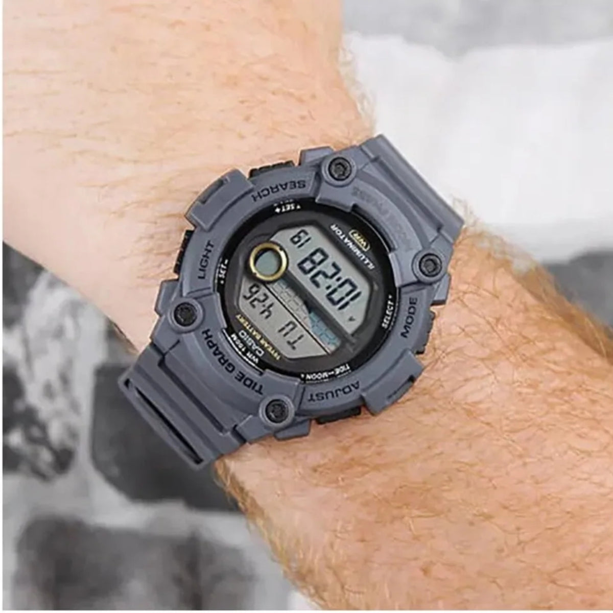 Men's digital watch worn on wrist, dark gray resin strap and moon phase display