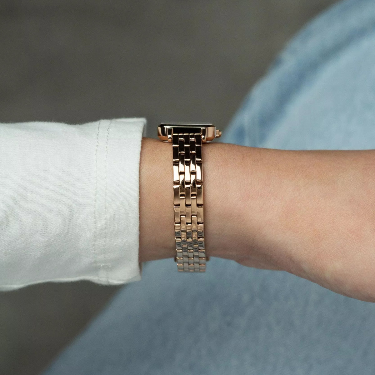 Rose-gold tone steel bracelet and square watch case on wrist, white mother-of-pearl dial