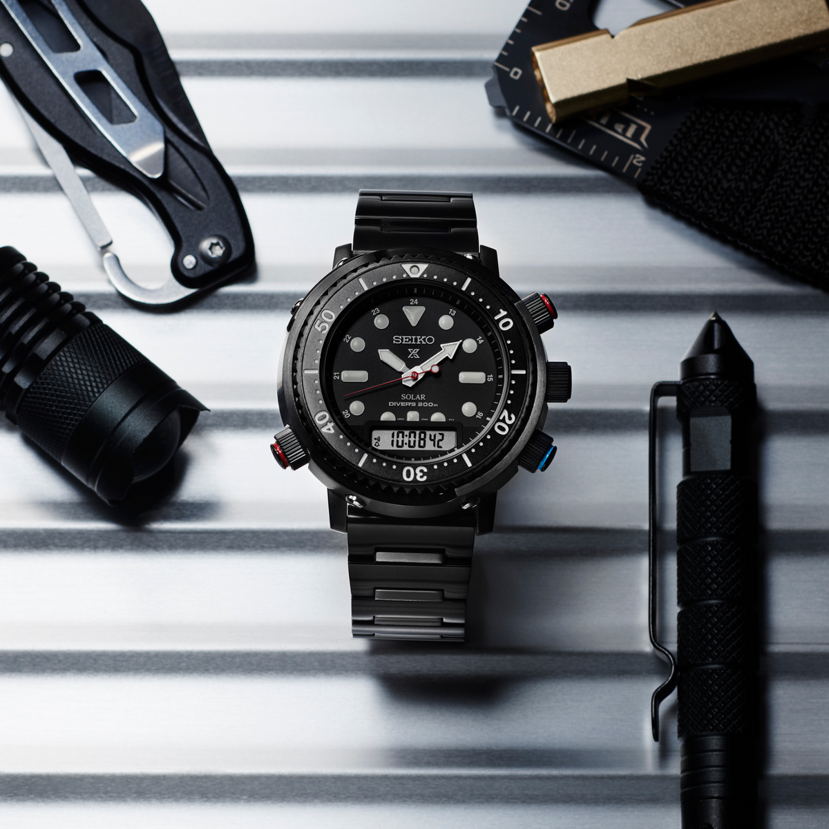 Black solar diver watch on tools, black dial with red-accent second hand