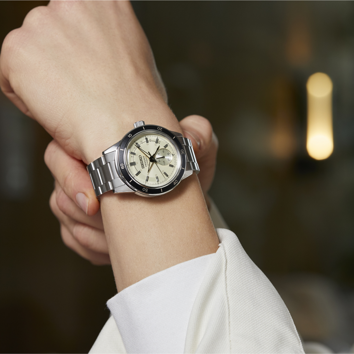 Men's stainless steel watch with ivory dial on wrist, metal bracelet and crown