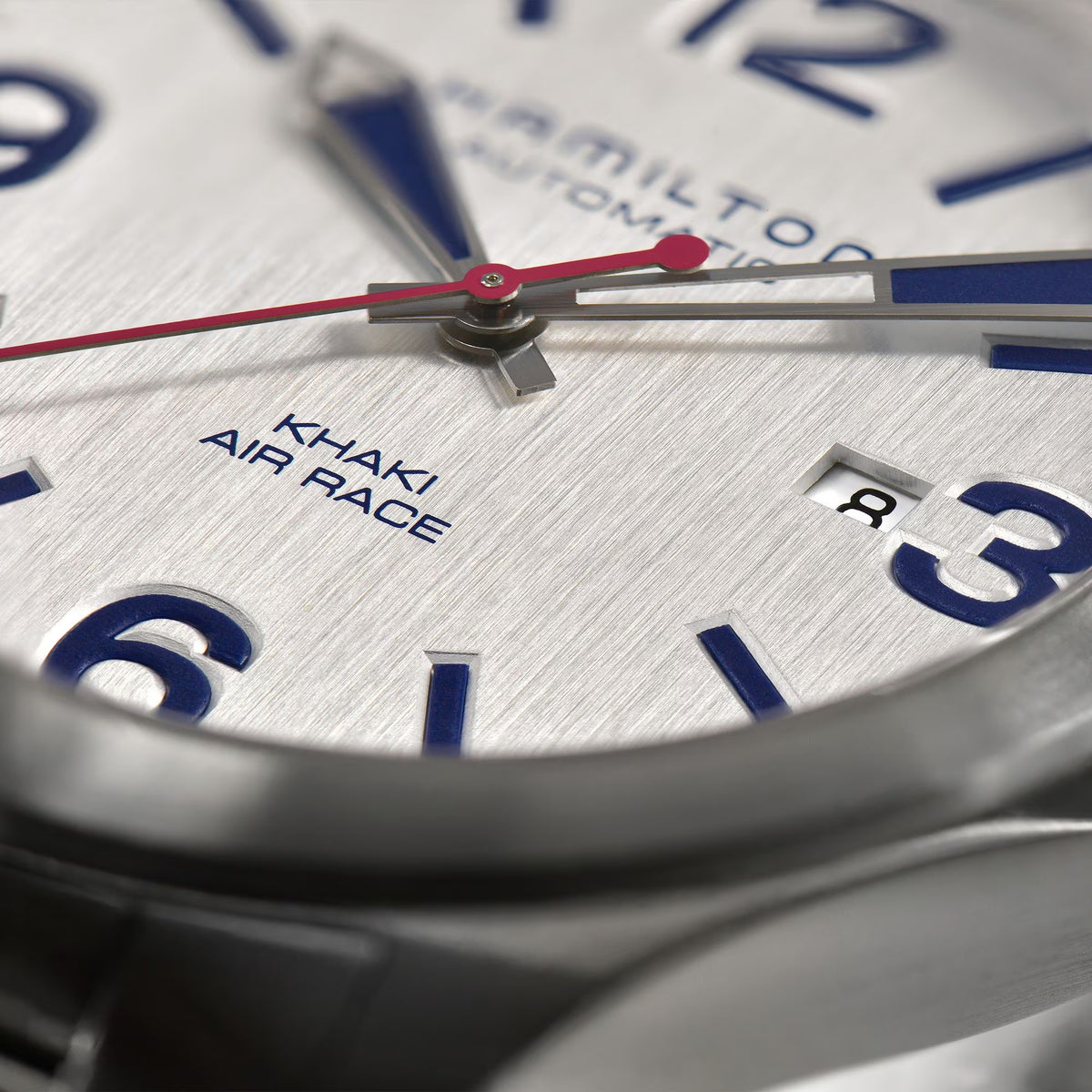 Men's white watch dial close-up with red center hand and blue time markers